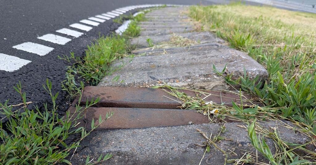 Løs metalklods og løse curbsten i indersiden af sving 1 på Ring Djursland